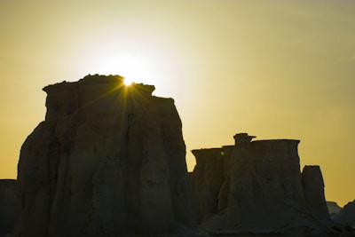 A silhouette of a Yowie figure carved into a large rock formation, bathed in warm sunset light.
