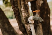 Hands fitting a PVC tap onto a water pipe outdoors in a garden setting.