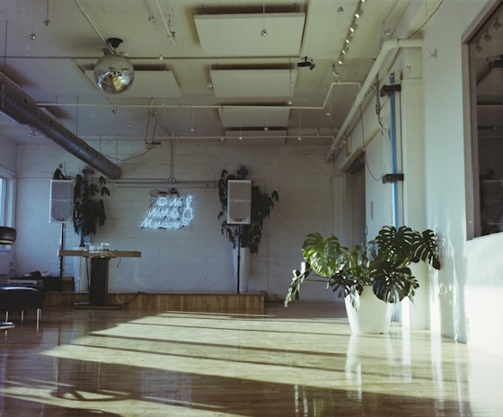 Bright and spacious rehearsal room with wooden floors and large windows.