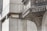 Detailed architectural features of a concrete structure including geometric patterns and reliefs. The forefront showcases a prominent overhang with intricate designs and textures, set against a background of additional concrete surfaces with a small, recessed window.