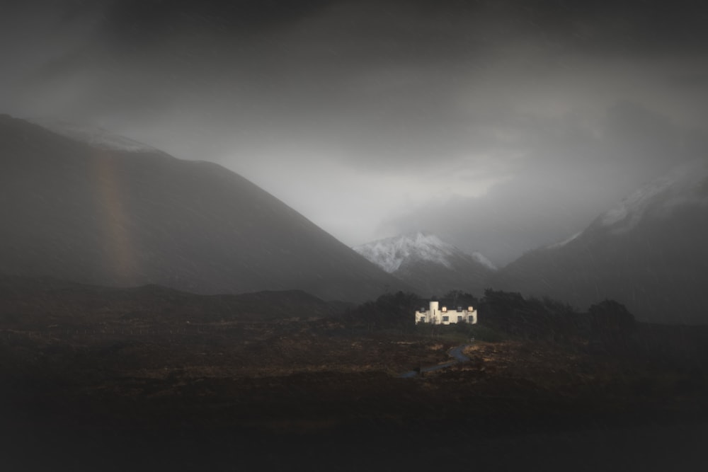 a house in the middle of a field with mountains in the background