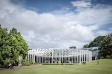 a large glass building sitting on top of a lush green field