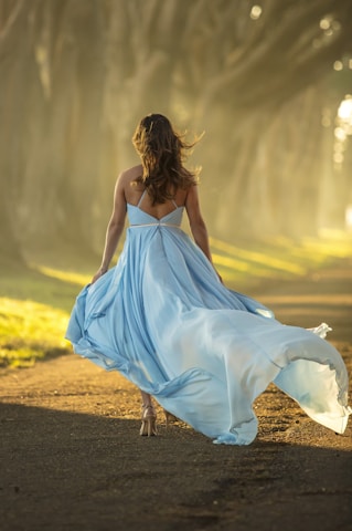 woman in blue dress walking on road during daytime