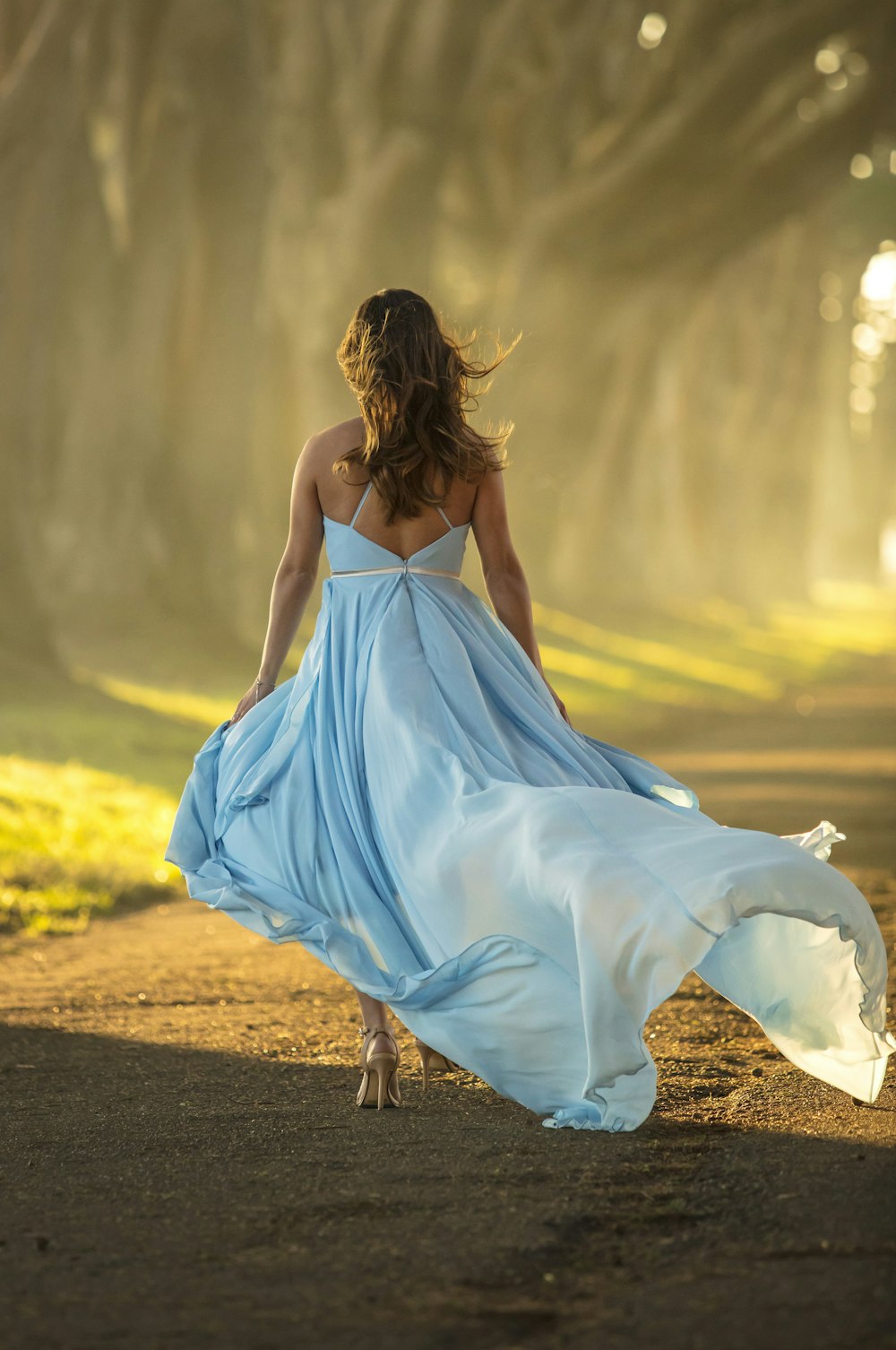 Mujer en vestido azul caminando por el camino durante el día
