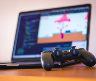 black laptop computer beside controller on brown wooden surface