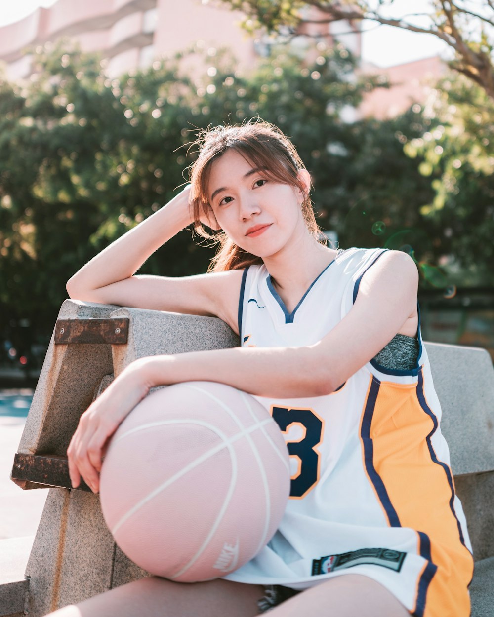 uma mulher sentada em um banco segurando uma bola de basquete