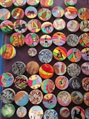 A collection of colorful, circular art pieces each featuring unique designs and patterns. The designs include abstract shapes, animals, people, and cultural motifs, with bold and varied color schemes.