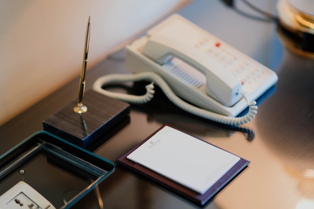 gold-colored sign pen with stand beside white IP telephone