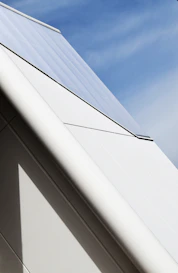 Close-up of a freshly installed roof with deep blue shingles under a clear sky.