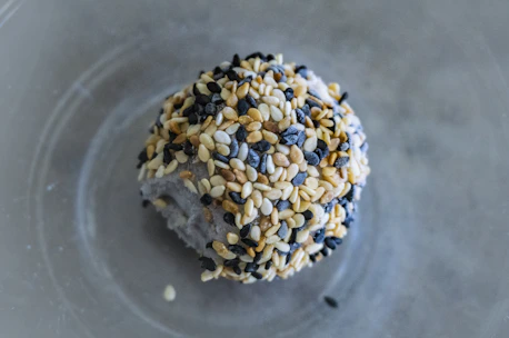 Close-up of fresh black and white sesame seeds with certification badges in the background.