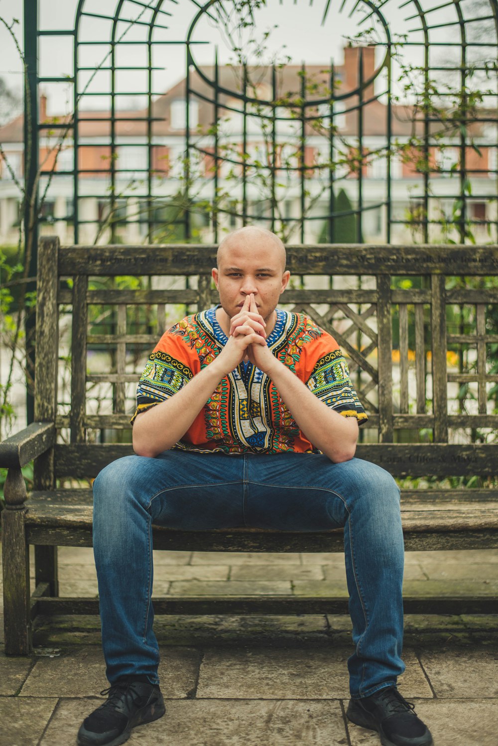 man wearing multicolored tribal shirt sitting on bench
