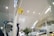 A modern airport interior with high ceilings and perforated panels. There are directional signs, including a yellow sign for Gate 7. The space is well-lit with overhead lights, and features glass railings and plants. A Wi-Fi symbol is visible, indicating connectivity services.