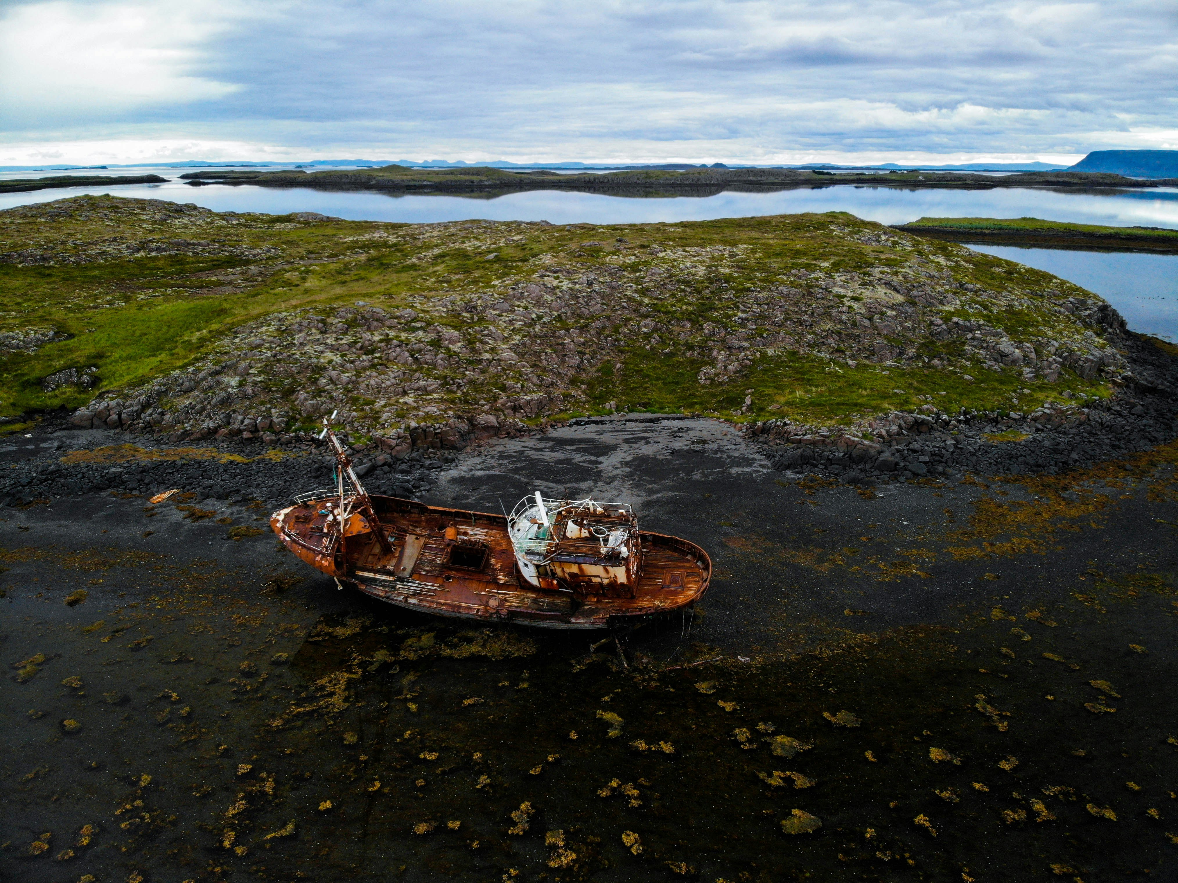 destroyed brown boat near rock