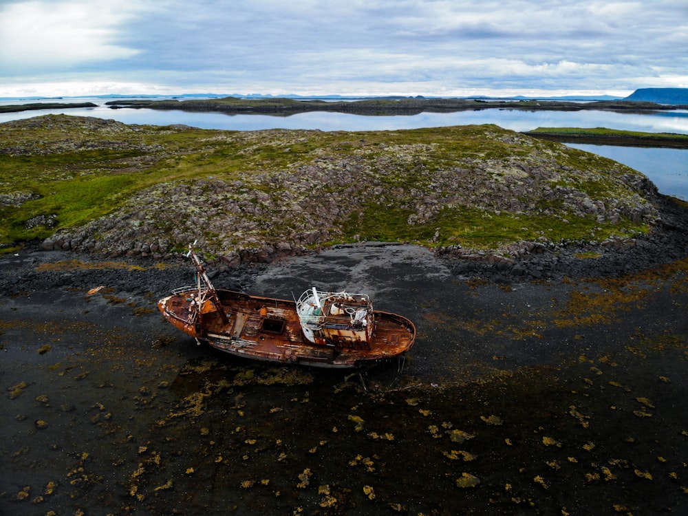 destroyed brown boat near rock