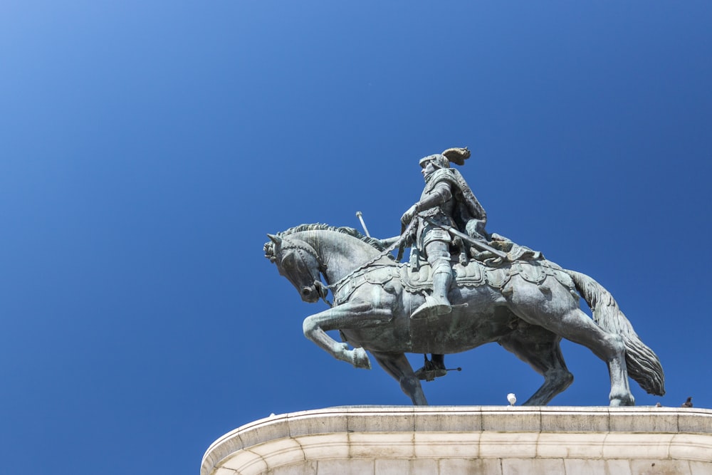 man riding horse statue under blue sky during daytime