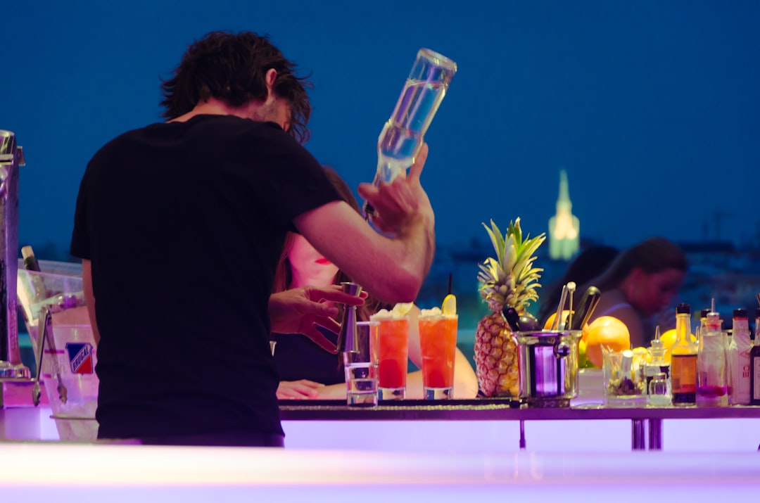 man in black t-shirt preparing tequila at the counter, Bartender making a drink at a rooftop bar in Madrid.