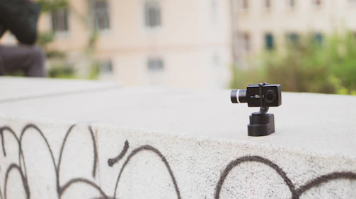 A creator filming a bustling urban street scene with a compact action camera mounted on a gimbal.