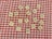 Scrabble tiles are scattered on a red and white checkered background. The tiles display various letters randomly placed across the surface.