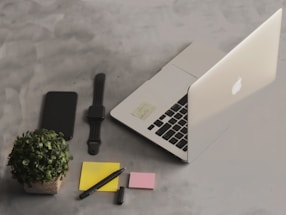 A sleek modern workspace with a laptop, smartphone, and notes.