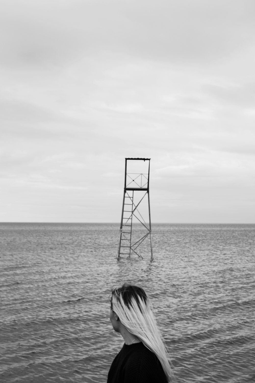 grayscale photo of woman standing beside water