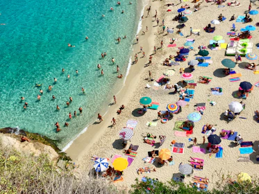 An overhead view of a lively Florida beach with sunbathers and turquoise waves.