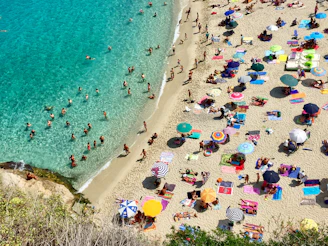 An overhead view of a lively Florida beach with sunbathers and turquoise waves.
