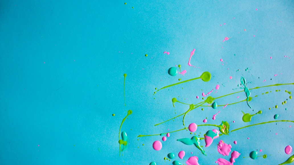 Colorful paint splats in bright teal and neon hues, representing creativity and expression.