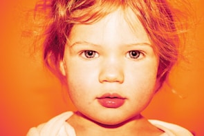 A close-up portrait of a child smiling with vibrant colors in the background.