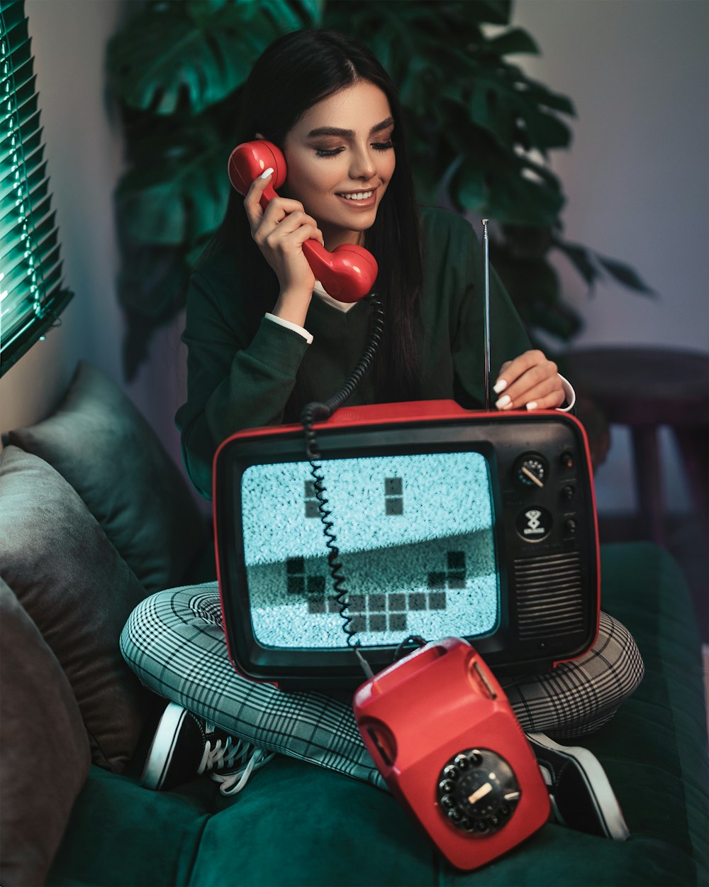 smiling woman sitting while using telephone and fixing antenna of radio