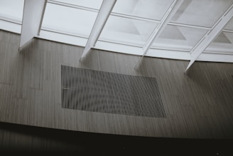 Glass panels create a modern architectural ceiling design with linear patterns visible through the framework. Below, vertical wooden slats form a minimalist aesthetic on the wall.