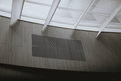 Glass panels create a modern architectural ceiling design with linear patterns visible through the framework. Below, vertical wooden slats form a minimalist aesthetic on the wall.
