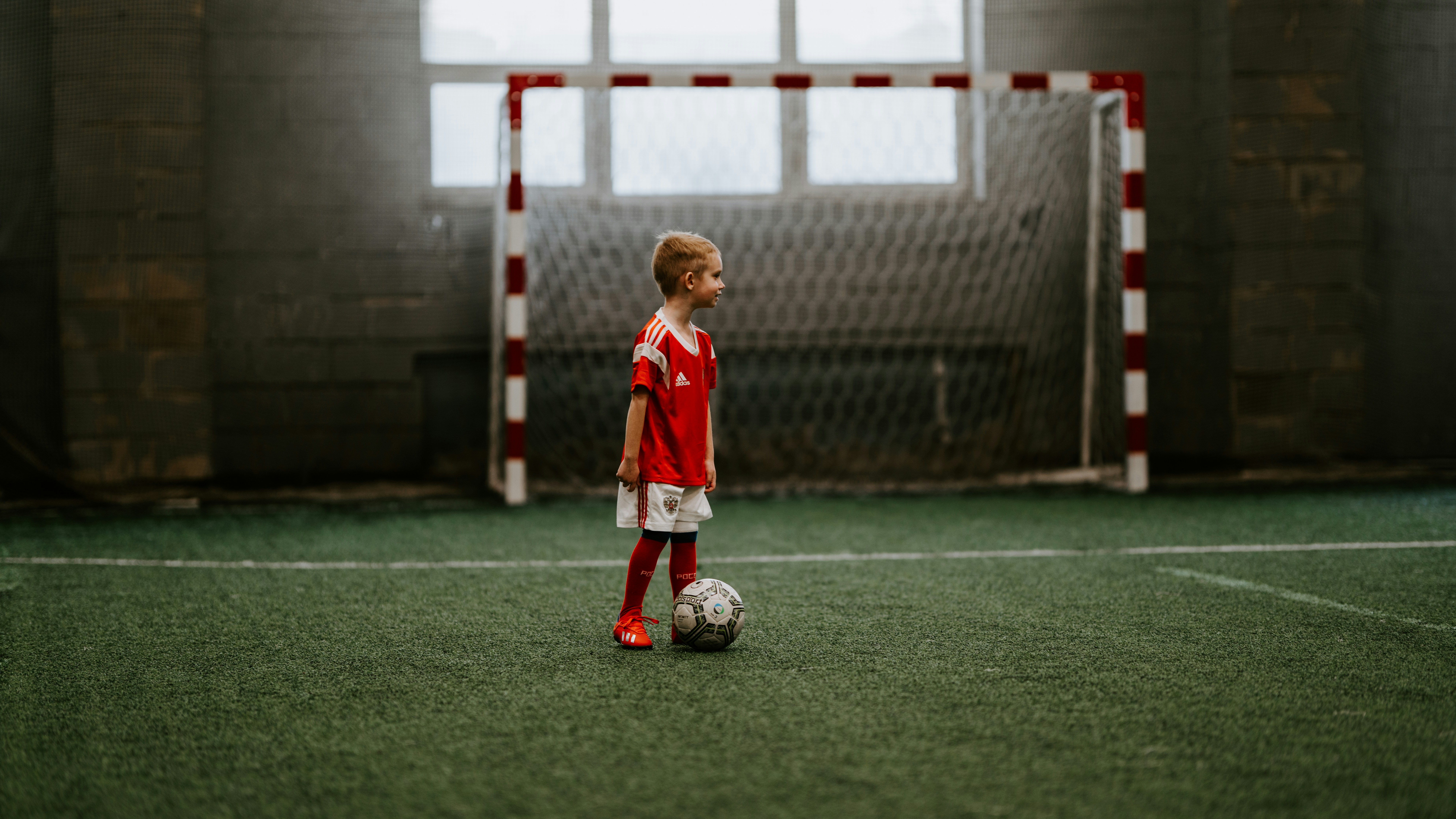 boy standing beside soccer ball near soccer net