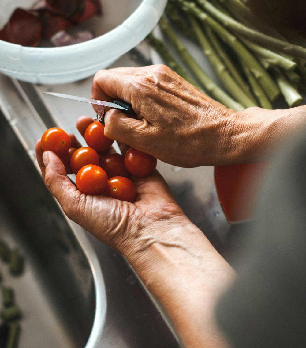 person holding knife and tomatoes