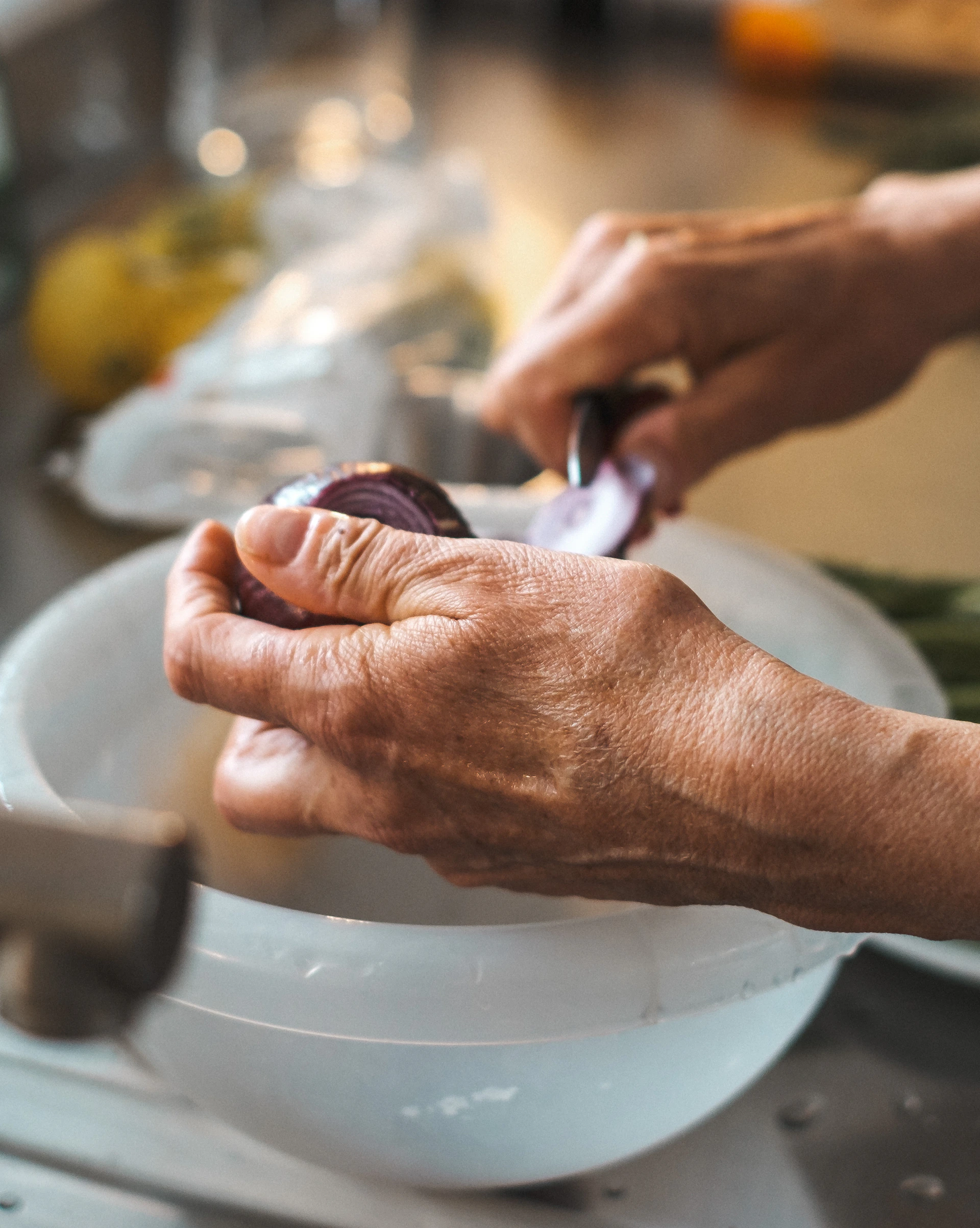 An expressive person wiping tears while chopping onions in a warmly lit kitchen, capturing the everyday moment explained by the blog.