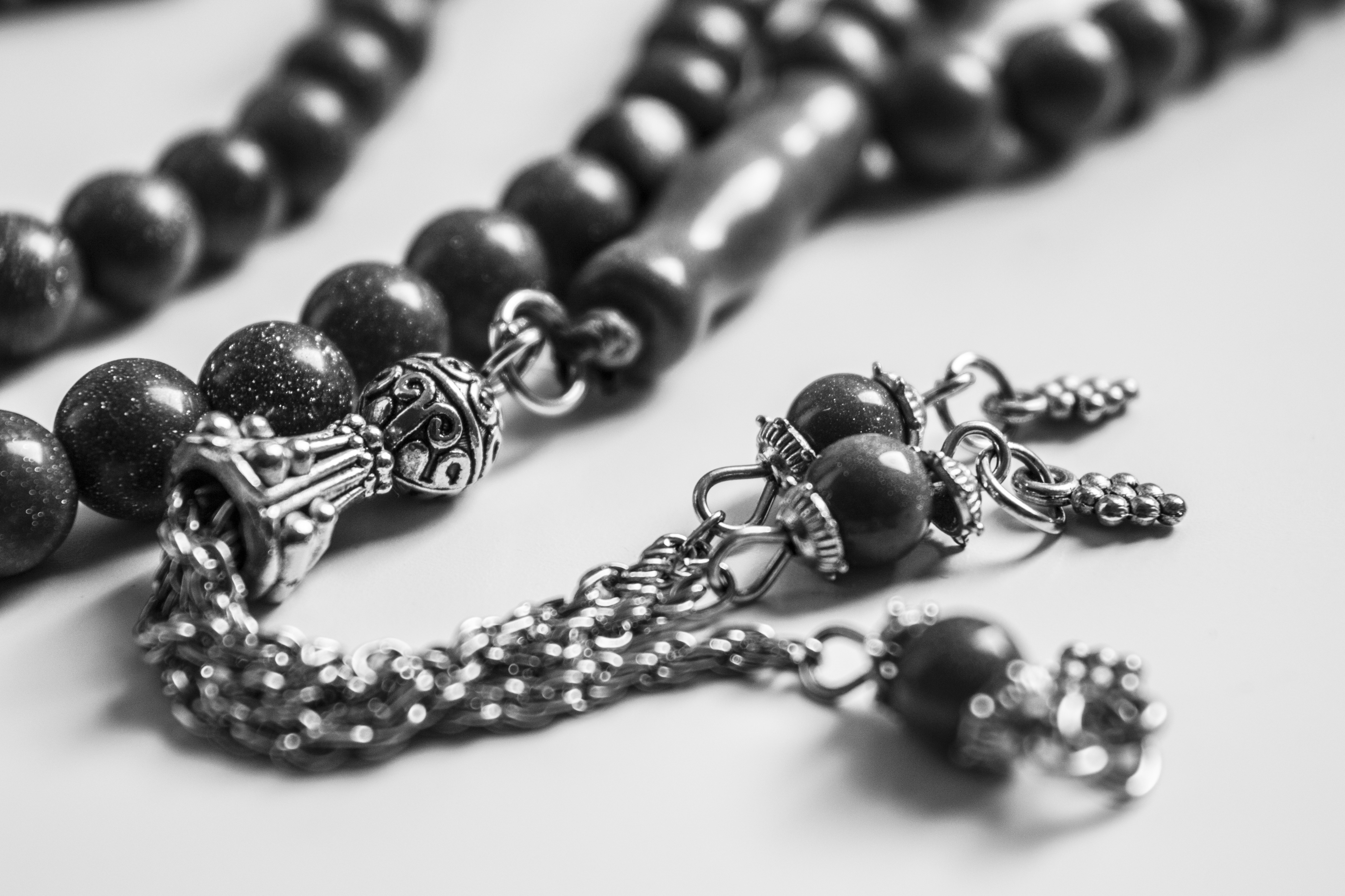 Silver inlaid prayer beads on white background, intricate metalwork detail