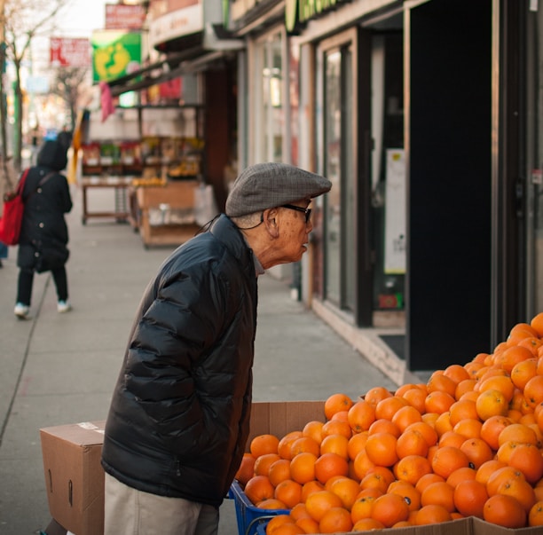 man standing beside orange fruits display
