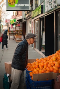 man standing beside orange fruits display