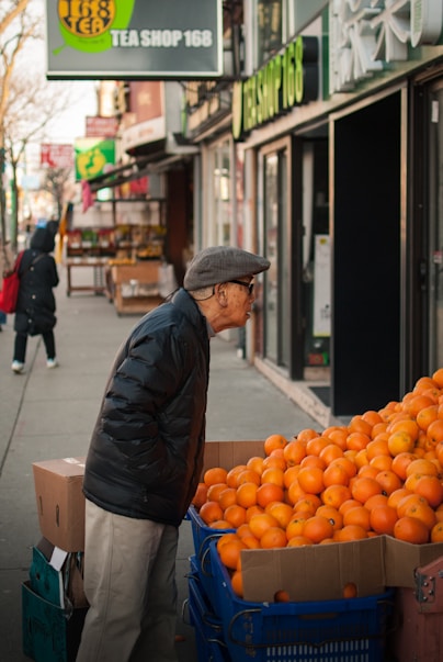 man standing beside orange fruits display