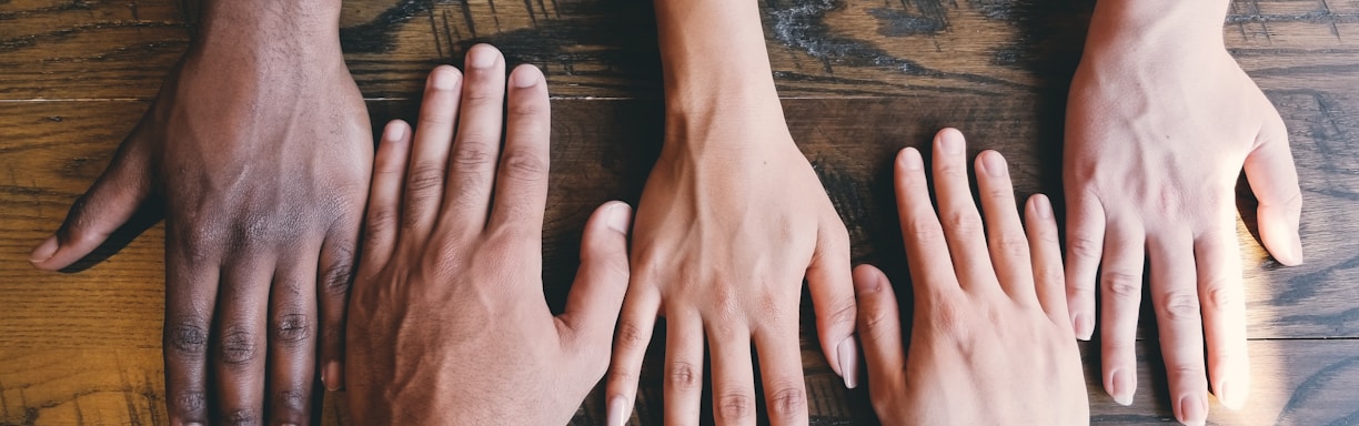 five human hands on brown surface