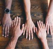 five human hands on brown surface