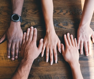 five human hands on brown surface