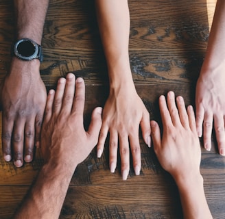 five human hands on brown surface