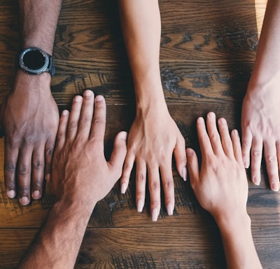 five human hands on brown surface