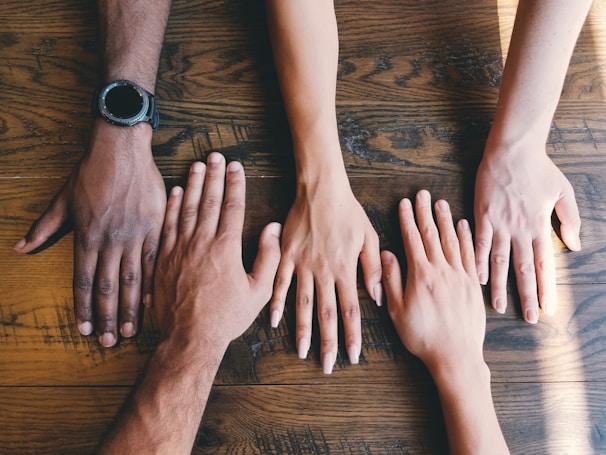five human hands, different skin colour on brown surface