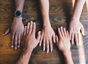 five human hands on brown surface