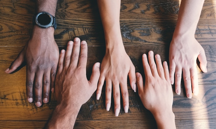 five human hands on brown surface