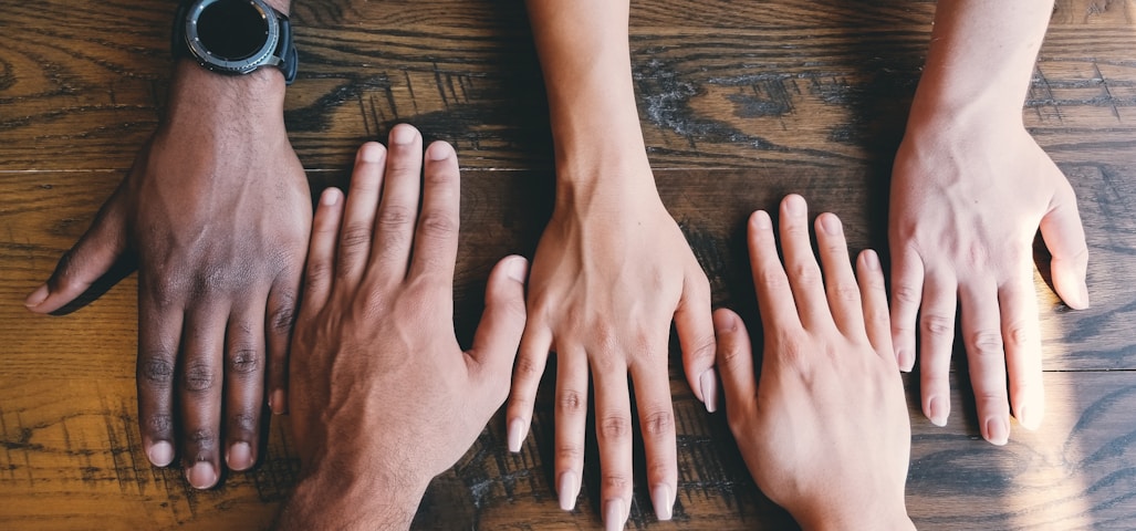 five human hands on brown surface