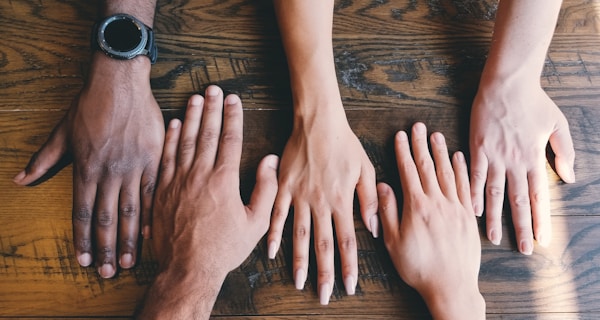 five human hands on brown surface