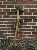 A vintage double-bit axe leaning against a rustic cabin wall.