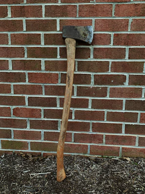 A vintage double-bit axe leaning against a rustic cabin wall.